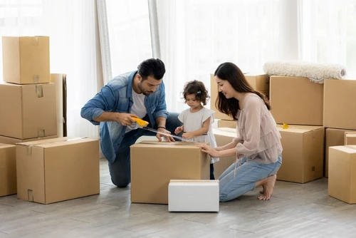 Parents and child packing cardboard boxes in preparation for a move.