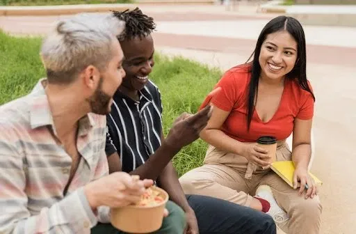 Diverse people having fun eating take away food outdoor in the city.
